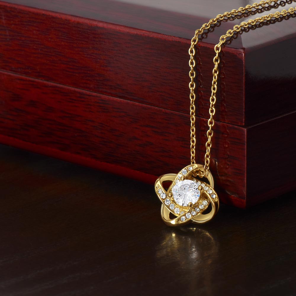 18K Yellow Gold Finish Love Knot Necklace on display draped over the mahogany style luxury gift box that comes with and LED light